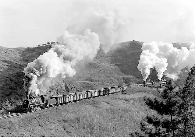 A loaded train climbs towards the first tunnel on the Chengde steelworks branch. It is headed by an SY 2-8-2 and banked by 2 JS 2-8-2s. February 1999