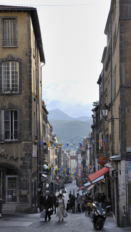 A view from the steps of Clermont Ferrand cathedral looking down a street - but above it is Le Puy-du-Dôme.